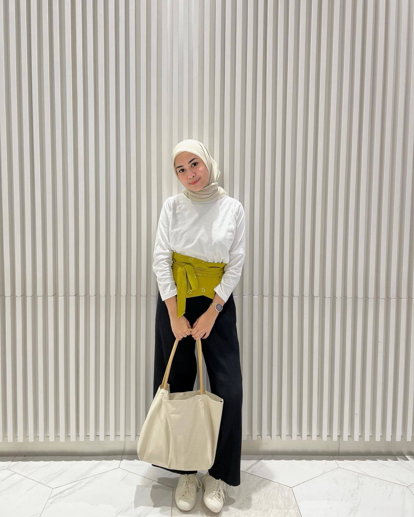 Wanita Indonesia mengenakan hijab dengan baju putih dan celana hitam.
