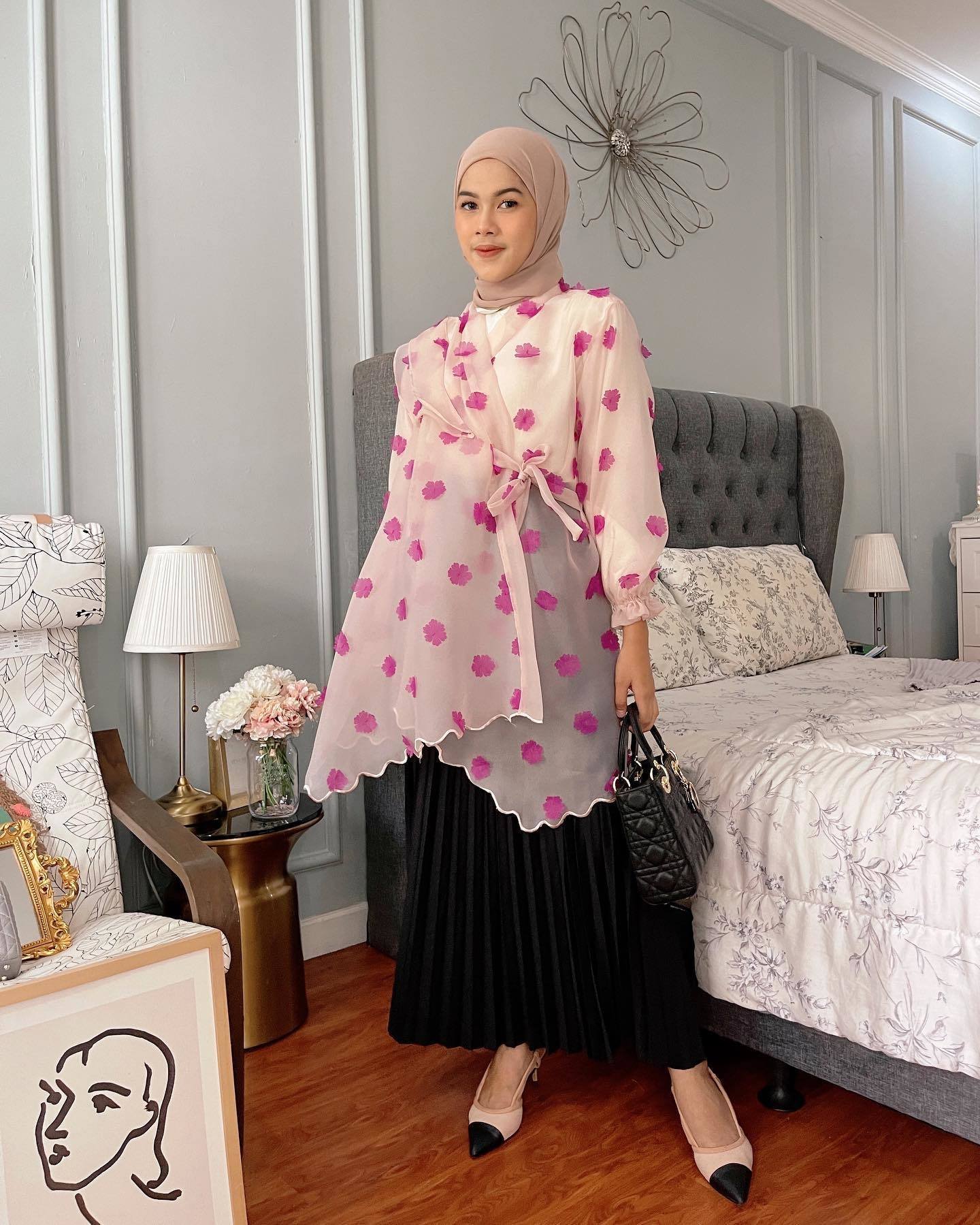 Wanita Indonesia mengenakan hijab warna nude yang dipadukan dengan baju berbahan organza warna pink yang mewah.